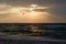 Stormy sea weather and lonely seagull hover in front of sunset sky full of warm light