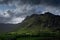 Stormy skies and a bright sun trace light over The Langdale Pikes in the English Lake District