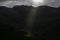 Stormy skies and a bright sun trace light over The Langdale Pikes in the English Lake District