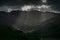 Stormy skies and a bright sun trace light over The Langdale Pikes in the English Lake District