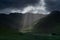 Stormy skies and a bright sun trace light over The Langdale Pikes in the English Lake District