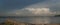 Stormy skies over a lake with driftwood on shore