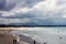 Stormy sky over beach at Byron Bay Australia with people playing silhouetted and swirling water reflecting sun from breaking