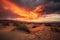 stormy sunset over desert, with orange and red hues reflecting off the sand