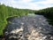 a stormy wide river with a green forest on both bergs