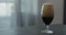 Stout beer drops slide from tulip glass on terrazzo countertop with copy space