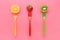 Straeberry lemon and kiwi on colorful forks on pink background juicy summer colors