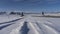 A straight asphalt highway runs through a snow-covered valley.