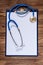 Straight clean vertical image with examination pad and stethoscope on the wooden background