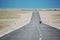 A straight flat asphalt road to the blue lake