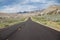 A straight and long road crossing a bushes field towards Kodachrome Basin State Park