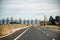 Straight open empty road surrounded by farms and fields in Australia. Mountains on the horizon. Road trip travel