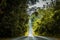 Straight road in countryside on hill slope surrounding by green trees inside tropical rainforest area