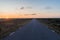 Straight road by sunrise in a great barren landscape