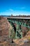 Straight truss bridge on high poles supports through canyon