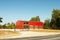 a straight-walled hangar, in the photo a production hangar against the background of trees and blue sky, a fence in the foreground