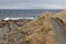 The Strait of Magellan at cloudy rainy day, trail along the stony shore with dry yellow grass. Patagonia, Chile.