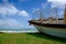 Stranded fisherman boat on green grass toward seaview at sunny day and cloudy blue sky