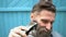 Strange man with beard trying to cut own hair with trimmer.