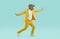 Strange man in yellow suit and funny dinosaur mask running and dancing on blue background
