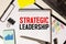 STRATEGIC LEADERSHIP text . Conceptual background with chart ,papers, pen and glasses