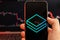 Stratis STRAX cryptocurrency logo on the screen of smartphone in mans hand with downtrend on the chart on a red light