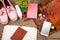 straw bag, smart phone, headphones, notepad, pink shoes, passport and book on wooden desk