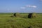 Straw bales on a field in the foreground.  Harvest of hay. Clouds in the sky. Agricultural farm. Hills with cultivated fields and