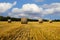 Straw bales on the field under blue sky with white clouds