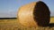 Straw ball in a field with wind farm in background