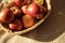 Straw basket with a lot of red ripe apples on bedcover background. Home harvest