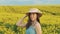 Straw beach sun hat lies on yellow flowers rape. Beautiful woman posing as model