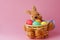 Straw bunny basket with easter colorful eggs on pink background. Happy Easter. Copy space. Close up