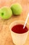 Straw in cup of juice and blur apple ,wood background.