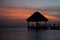 Straw gazebo silhouette against sunset sky