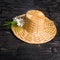 Straw hat with daisies flower on black cracks background, close