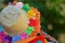 A straw hat filled with small colored ribbons and orange lace and ribbon braid