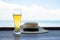 straw hat and glass of beer on wooden table on seaside background