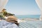 Straw hat lying on the beach bed with beauty view to blue the ionian sea, clear sky and girl in water on Greek island Zakynthos