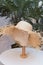 Straw hat on a mannequin. Brown hat on an empty mannequin in a store on a background of palm leaves