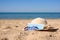 A straw hat, sunglasses and a medical mask lie on the beach by the sea.