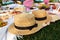 Straw hats lay on a white picnic blanket at green lawn bright summer day background. Summer weekends leisure