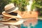 Straw hats stack at the pool edge with palm reflections in the water. Private pool in the asian style garden