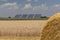 Straw roll bales detail with crop field, photovoltaic panel and blue sky in background