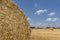 Straw roll bales detail with crop field, photovoltaic panel and blue sky in background