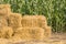Straw square bale against a green field of corn, bales of hay on a country road