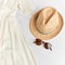 Straw stylish hat, sunglasses and polka dot white dress on white background