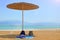 Straw umbrella, backpacks and bedspread on a sandy beach by the water. Tourism and rest on the Dead Sea in Israel