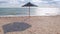 Straw umbrella on empty sand beach with harsh shadow, vivid blue sea water sky background sunbeam. Scenic landscape new normal