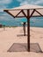 Straw umbrellas on green grass harsh shadow, sand beach vivid blue sea water sky background sunbeam. Scenic landscape